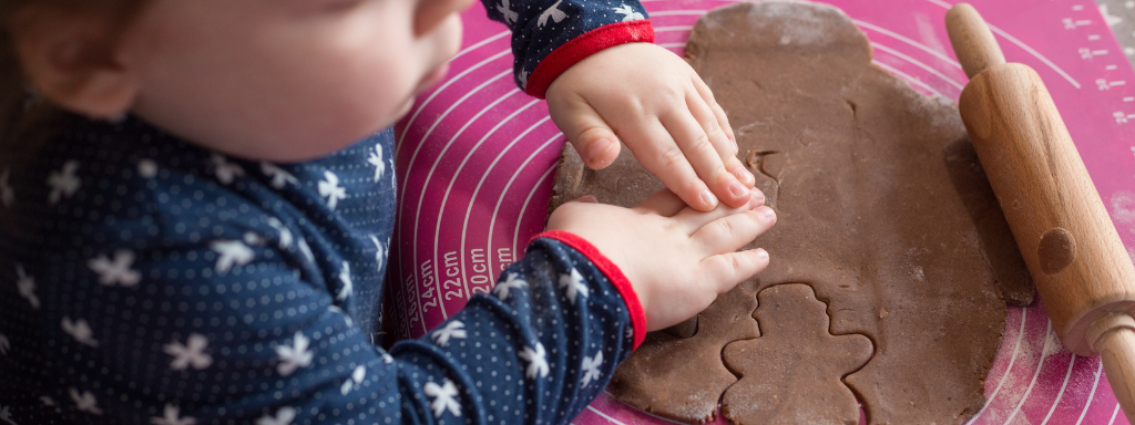 toddler baking ideas - the photo shows a child pressing a gingerbread cutter into dough