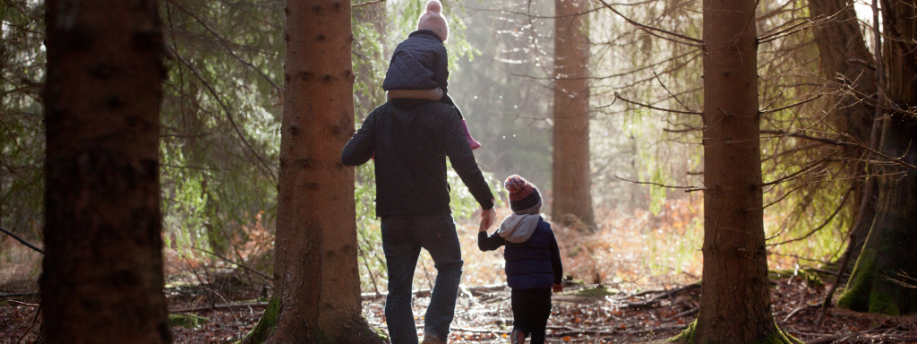outdoor spring activities for kids - the photo shows a family walking through a wood